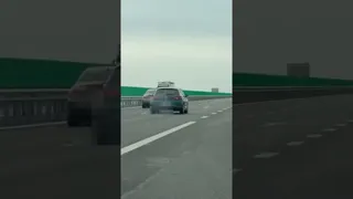Două mașini circulă pe o autostradă cu linii de demarcare albe pe asfaltul gri sub un cer închis.