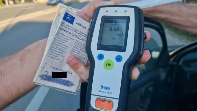 O persoană ține un aparat de testare a alcoolului cu afișajul digital și un certificat de înmatriculare într-o mână, lângă o mașină.