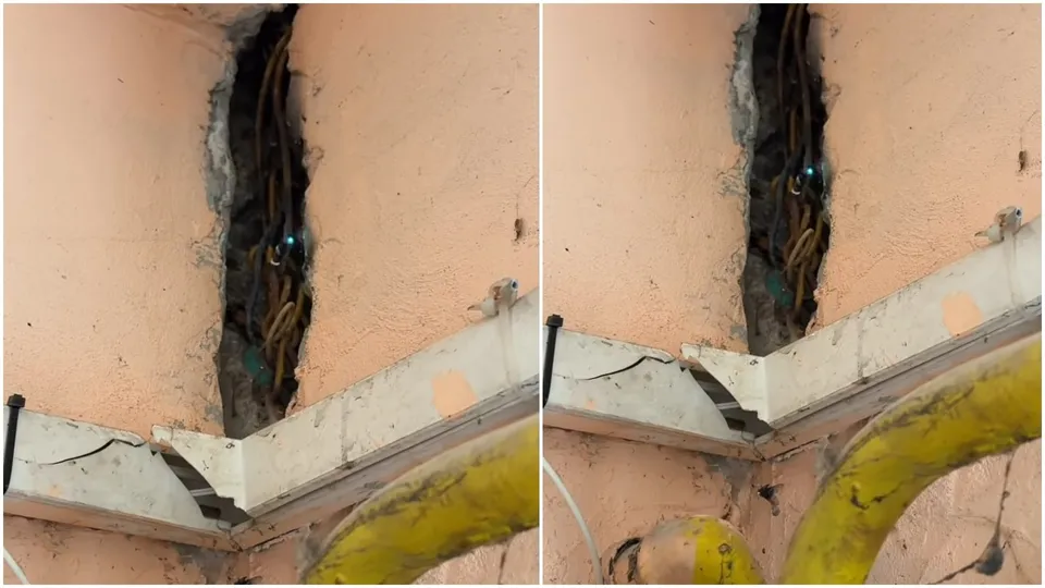 Cabluri electrice sunt vizibile într-o șanțură verticală practicată într-un perete de culoare roz des.